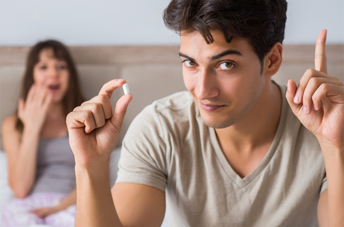 Young man in bed with wife about to take Stamina for Men instant erection pill